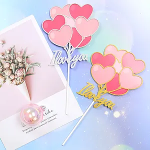 Close-up of glittery pink heart balloon cake toppers featuring I love you cursive text