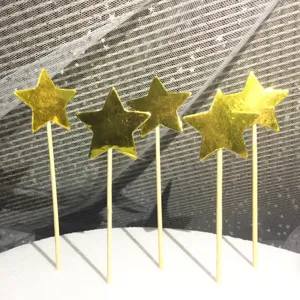 Dettaglio di cinque topper per torta a forma di stella dorata con bastoncini in legno