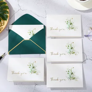 Détail de cartes de remerciement élégantes avec feuilles vertes et enveloppe vert foncé.