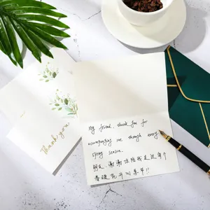 Gros plan d'une carte de remerciement avec message manuscrit et enveloppe verte