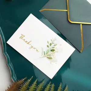 Détail d'une élégante carte de remerciement avec motif floral et enveloppe dorée