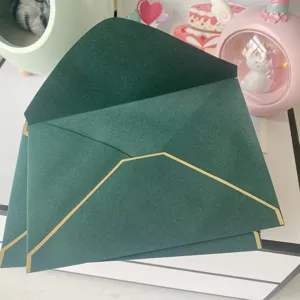 Gros plan d'élégantes enveloppes vert foncé avec bordure dorée pour invitations