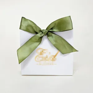 Detail van witte geschenkdoos met olijfgroen satijnen lint voor Eid al-Adha snoepverpakking.