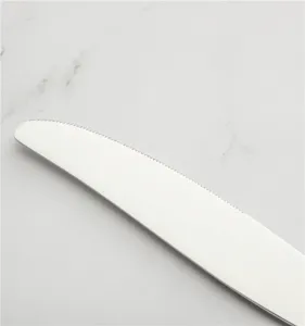 Dettaglio macro che mostra il bordo seghettato di un coltello da bistecca in inox