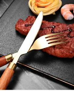 Detailansicht von Steakmesser und Gabel aus goldenem Edelstahl mit Sapele-Holzgriffen