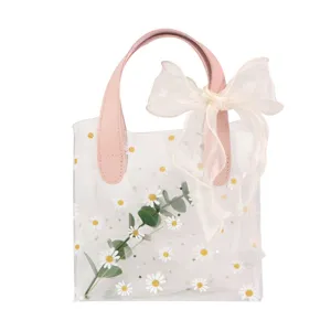 Elegante bolsa de regalo transparente de PVC con margaritas, asas rosas y lazo blanco