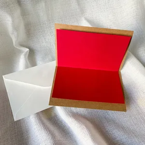 Kraftpapier-Grußkarte mit roter Innenseite und weißem Umschlag für Urlaubsgrüße.