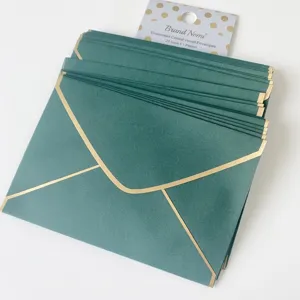 Pile d'enveloppes vert émeraude de qualité avec bordure dorée pour invitations de mariage.