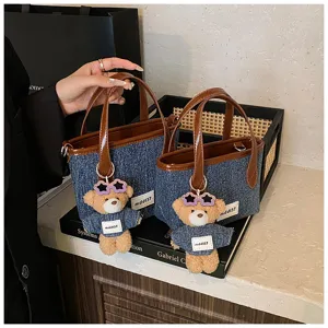 Detailed view of denim blue bucket bags with cute teddy bear charms and brown leather handles