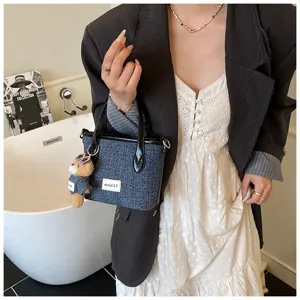Detail view of denim blue bucket bag featuring a stylish mini bear keychain charm