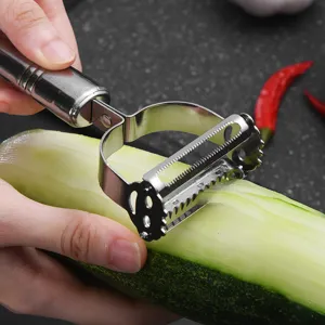 Gros plan d'un éplucheur en acier inoxydable épluchant un concombre vert dans une cuisine.