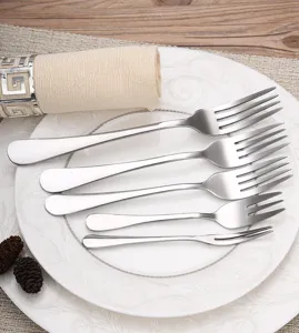 Set of five different sized stainless steel dinner and dessert forks on a white plate.