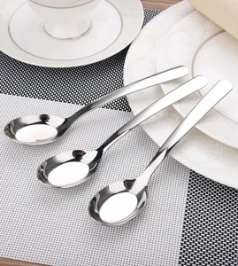 Close-up of three 304 stainless steel long-handle soup spoons on a white plate.