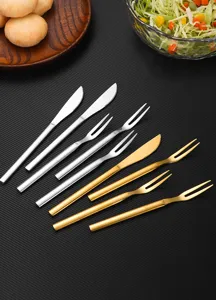 Detail view of gold and silver stainless steel fruit cutlery sets on a dark background