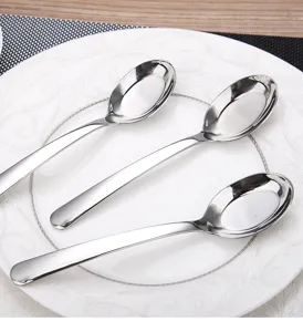 Detailed view of polished 304 stainless steel flat-bottom spoons on a ceramic plate