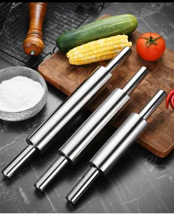 Detail view of three different sized stainless steel rolling pins on a wooden board