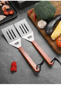 Detailed view of heavy-duty BBQ spatulas with wooden handles and built-in bottle openers.