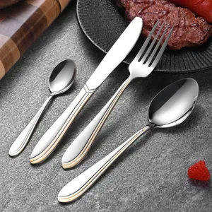 Elegant stainless steel cutlery set with double gold line handles on a stone background