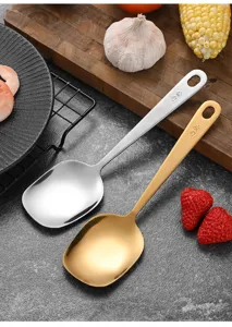 Detailed view of polished silver and gold stainless steel serving spoons with flat bowls.