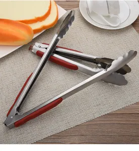 Stainless steel food tongs with red non-slip handles and scalloped heads for serving.