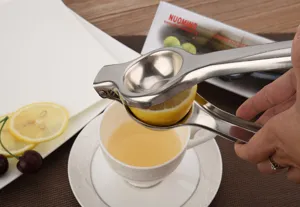 Detailed close-up of a manual stainless steel lemon squeezer pressing fresh fruit juice