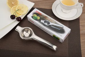 Stainless steel manual lemon squeezer and retail box shown on a modern kitchen table