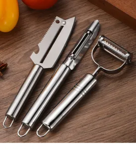 Detail view of three professional stainless steel kitchen peelers on wooden background