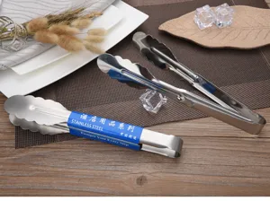 Detailed view of stainless steel scalloped food tongs set on a dining table scene.
