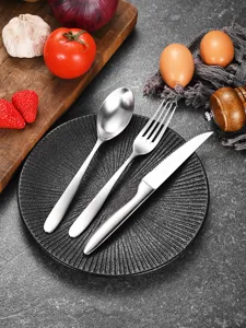 Close-up of matte stainless steel cutlery set including steak knife, fork, and spoon