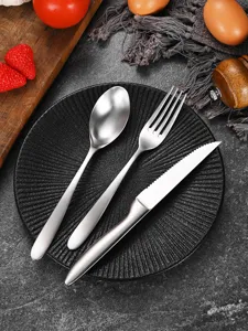 Brushed stainless steel cutlery set with steak knife, fork, and spoon on black plate.