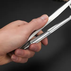Hand holding stainless steel oil filter tongs for frying and straining food