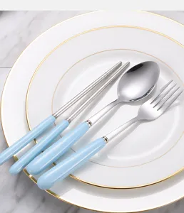 Close-up view of stainless steel cutlery set with light blue handles on white plate