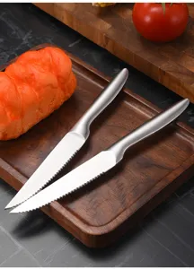 Detail view of two sharp serrated stainless steel steak knives with ergonomic satin finish