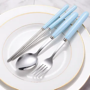 Light blue ceramic handle stainless steel spoon fork and chopsticks cutlery set on white plate