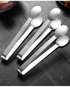 Close-up of three stainless steel ice tongs with serrated edges on a dark stone background