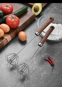 Pair of stainless steel semi-automatic egg whisks with wood grain handles on a kitchen counter