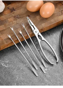 Close-up of stainless steel crab cracker and forks set on a stone kitchen countertop.