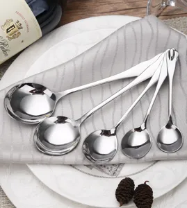 Detailed view of five polished stainless steel round spoons in varied sizes on a napkin.