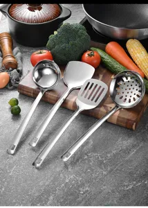 Primer plano de cuatro utensilios de cocina de acero inoxidable sobre una tabla de madera.