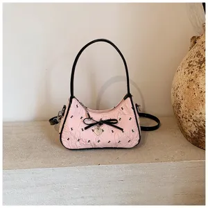 Fashionable pink crescent shoulder bag with crinkled texture and black bow charm