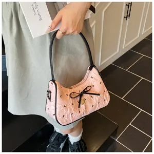 Close-up detail of a pink crescent handbag with bow accent and K-letter print pattern
