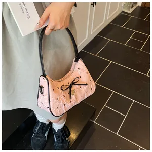 Close-up detail of a stylish pink crescent hobo bag featuring a black bow and pattern