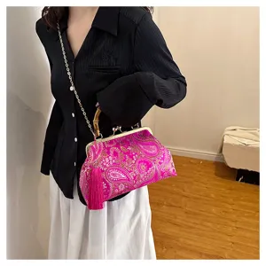 Detailansicht einer magentafarbenen Abendtasche mit Stickerei, Bambusgriff und Quaste.