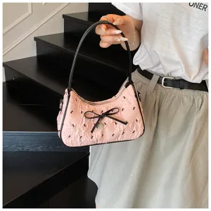Close-up view of a pink crescent hobo bag featuring a black bow and chic K pattern print