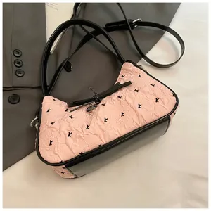 Detail view of pink hobo bag with bow and black trim on stylish blazer background.