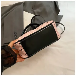 Close-up of pink pleated moon bag with black reinforced base and delicate bow prints