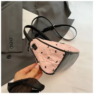Detail view of a pink crescent handbag with black bow prints and crinkled texture.