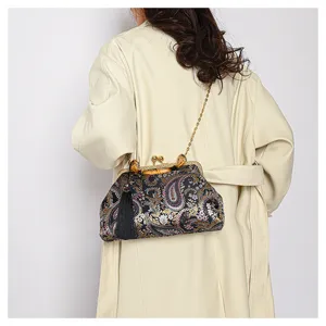 Detail einer Vintage-Handtasche mit Paisley-Stickerei, Bambusgriff und Goldkette.