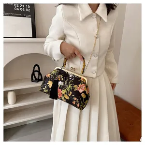 Sac élégant brodé de fleurs avec poignée en bambou et pompon noir sur costume en tweed blanc