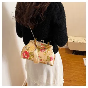 Gros plan d'un sac à main brodé de fleurs vintage avec poignée en bambou et pompon